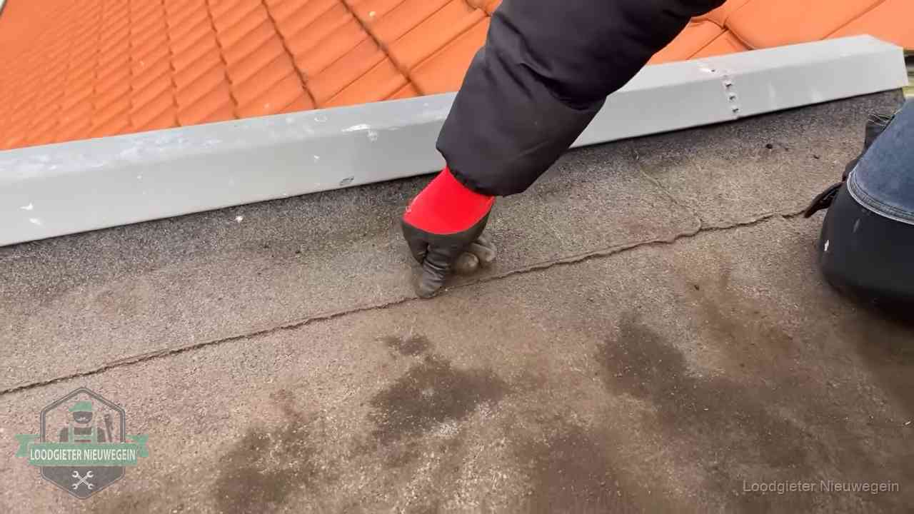 Lekkage bij de naad van een plat dak in Nieuwegein Vakman wijst een naad met vochtplekken aan op een bitumen plat dak in Nieuwegein