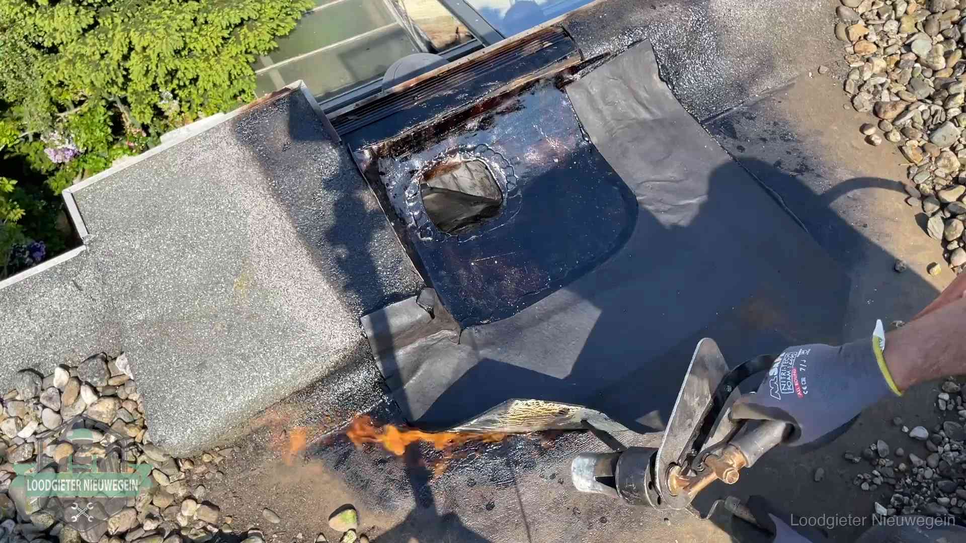 Daklekkage repareren in Nieuwegein Dakdekker brandt bitumen rond een doorvoer tijdens een daklekkage-reparatie in Nieuwegein