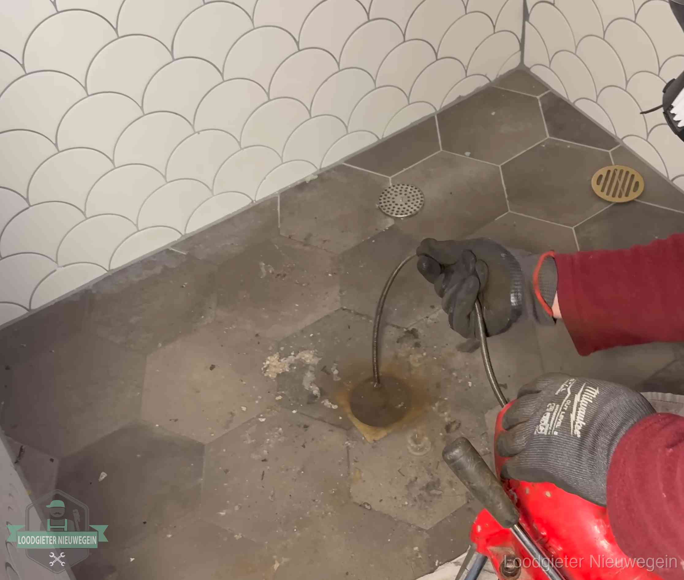 Ontstoppingsveer gaat in een geopend doucheputje in Nieuwegein waar het water omhoogkwam