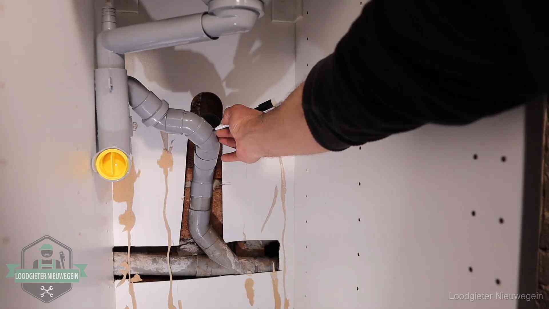 Loodgieter voor verhuurders en bedrijven in Nieuwegein Loodgieter markeert een pvc-afvoerbuis onder een gootsteen in Nieuwegein