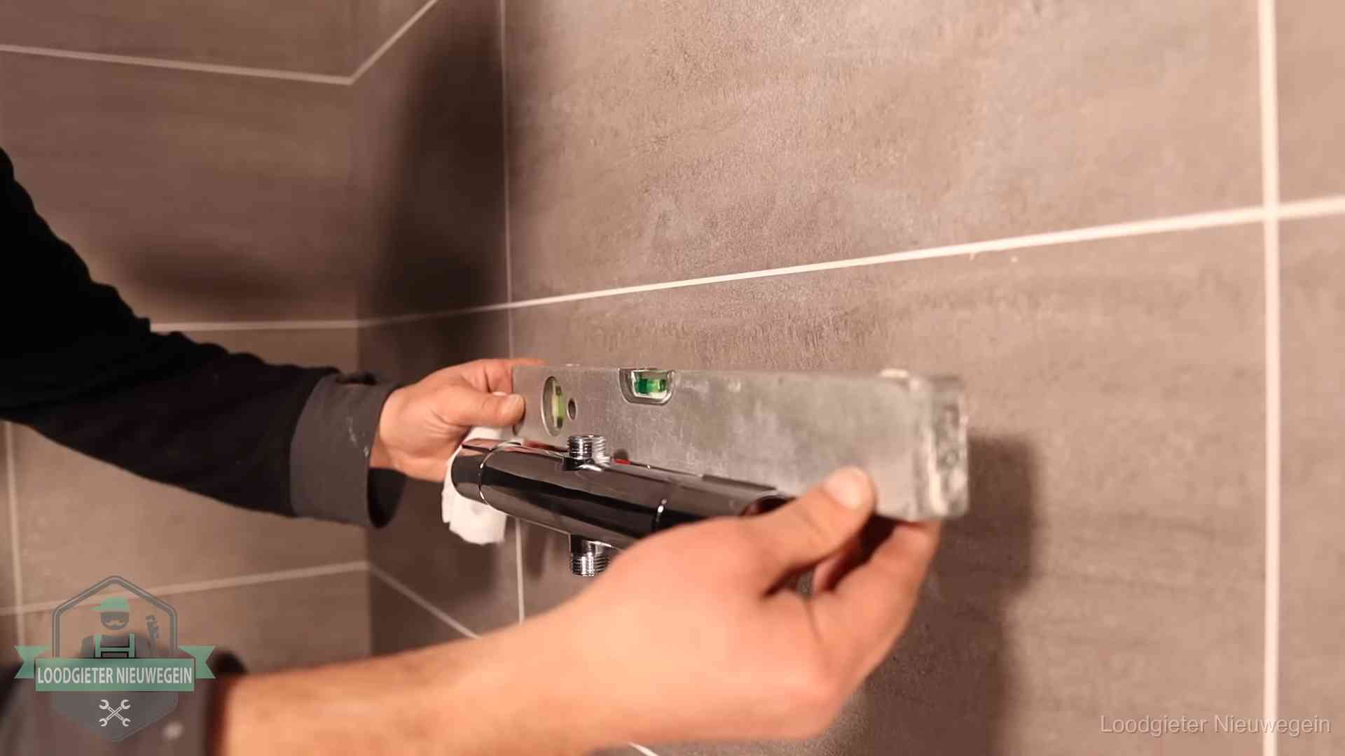Loodgietersbedrijf voor sanitair in Nieuwegein Loodgieter lijnt een douchekraan uit met een waterpas in een woning in Nieuwegein