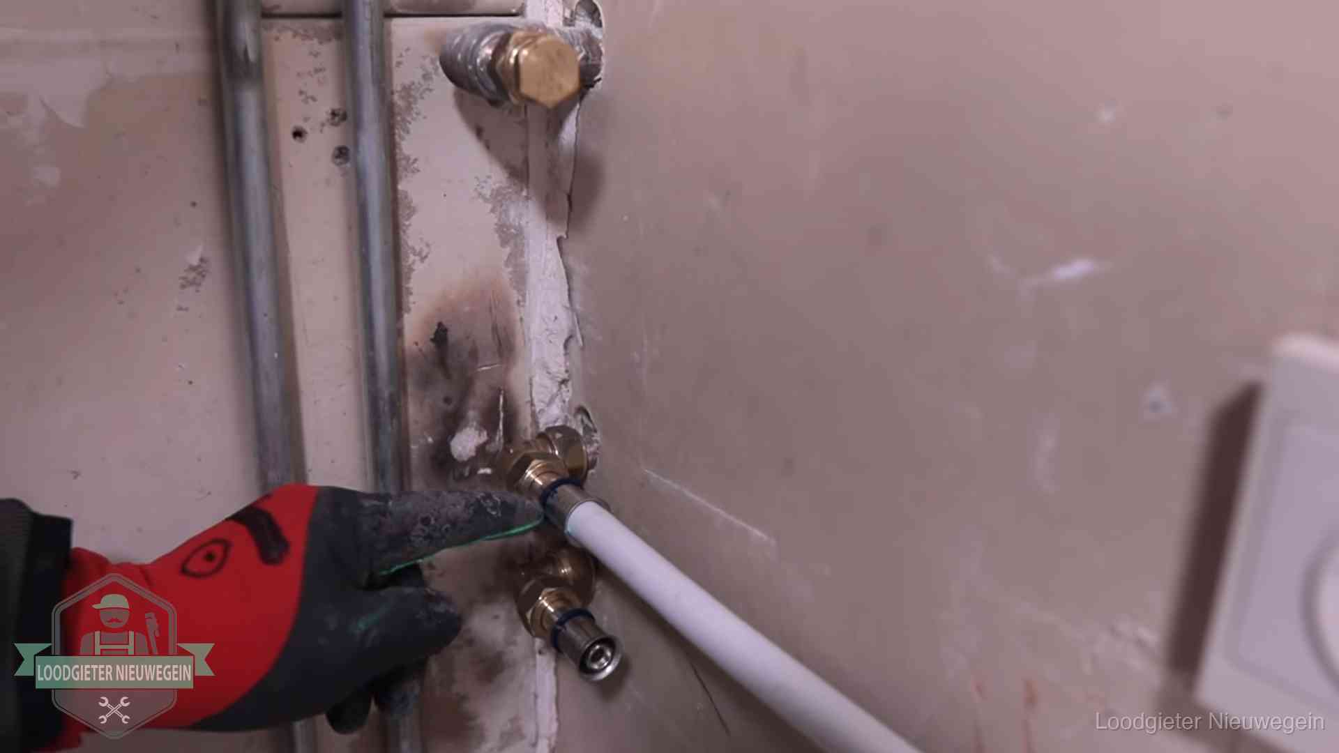 Garantie op loodgieterswerk in Nieuwegein Loodgieter wijst de persfitting op nieuwe muuraansluitingen aan in een woning in Nieuwegein