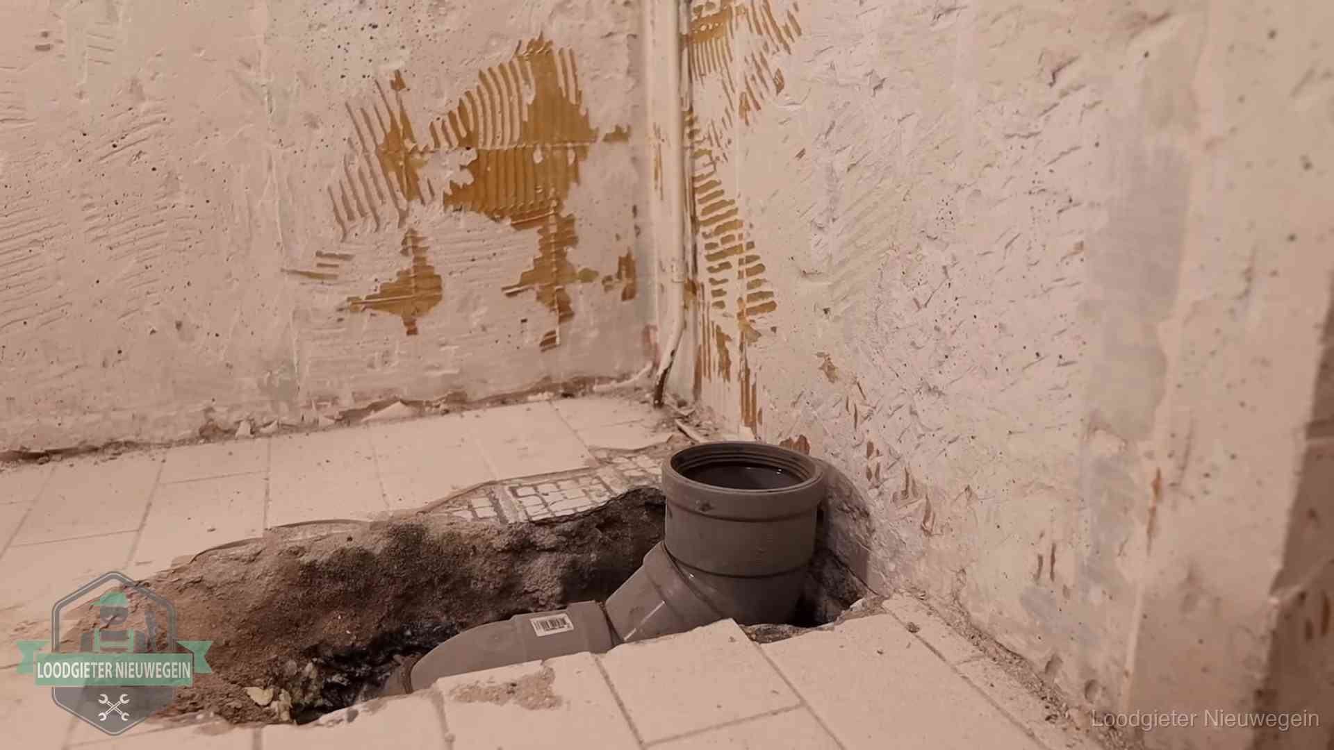 Opengebroken vloer met een nieuwe pvc-rioolbocht in een gegraven sleuf in Nieuwegein